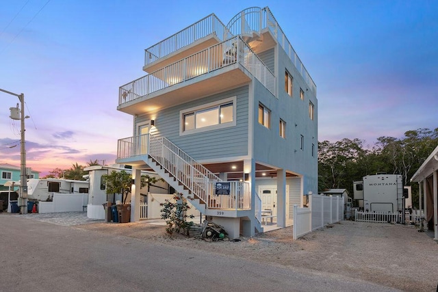 view of front of house featuring a balcony, stairway, and fence