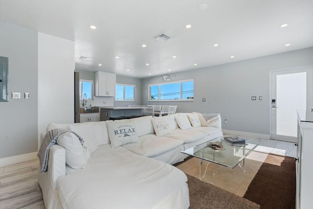 living room featuring recessed lighting, baseboards, and electric panel