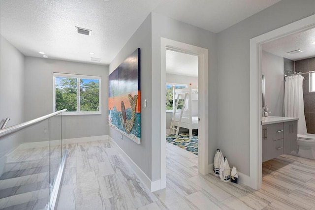 corridor with a textured ceiling and baseboards