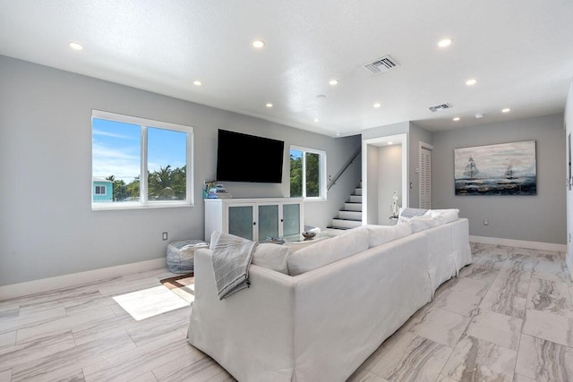 living area with recessed lighting, stairs, and baseboards