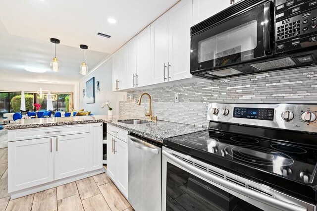 kitchen featuring appliances with stainless steel finishes, white cabinetry, a sink, and a peninsula