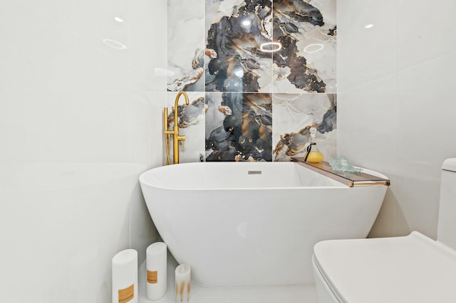 bathroom with a soaking tub, tile walls, and toilet