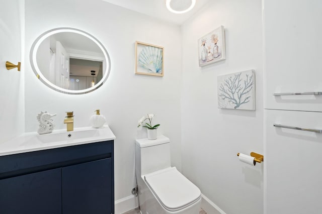 half bath with toilet, baseboards, and vanity