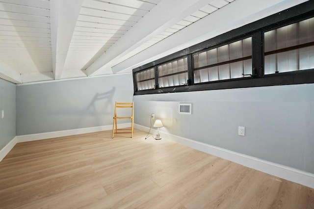 spare room with beamed ceiling, wood finished floors, visible vents, and baseboards