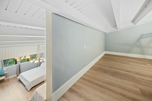 interior space featuring baseboards, beam ceiling, and wood finished floors