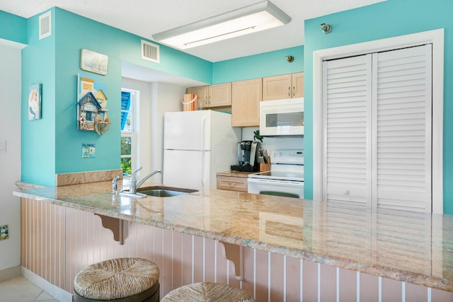 kitchen with light brown cabinetry, sink, a kitchen breakfast bar, kitchen peninsula, and white appliances