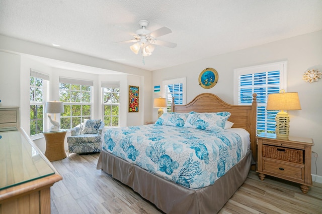 bedroom featuring ceiling fan, a textured ceiling, and light wood-type flooring