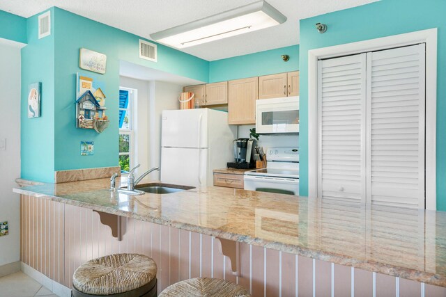 kitchen featuring light tile patterned flooring, dishwasher, sink, white fridge, and light stone counters