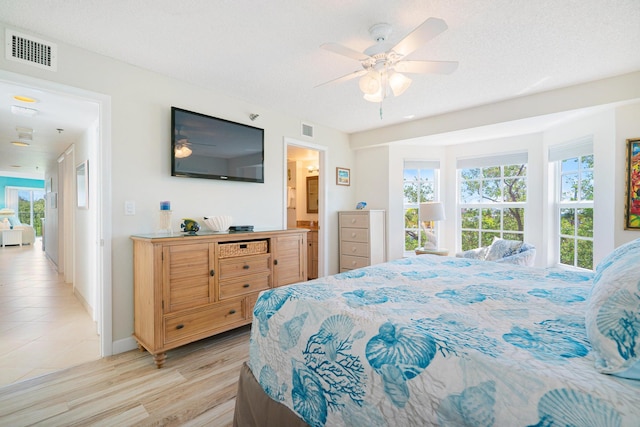 bedroom featuring multiple windows, light hardwood / wood-style flooring, and a textured ceiling