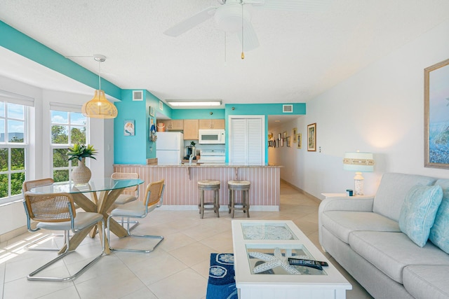 tiled living room featuring ceiling fan and a textured ceiling