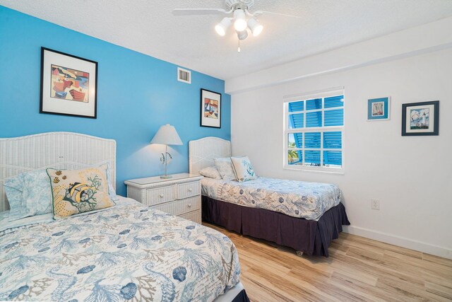 bedroom featuring ceiling fan, light hardwood / wood-style floors, and a textured ceiling