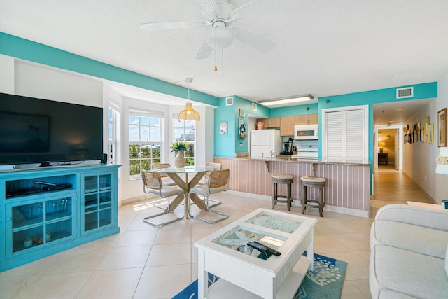 tiled living room with ceiling fan and a textured ceiling