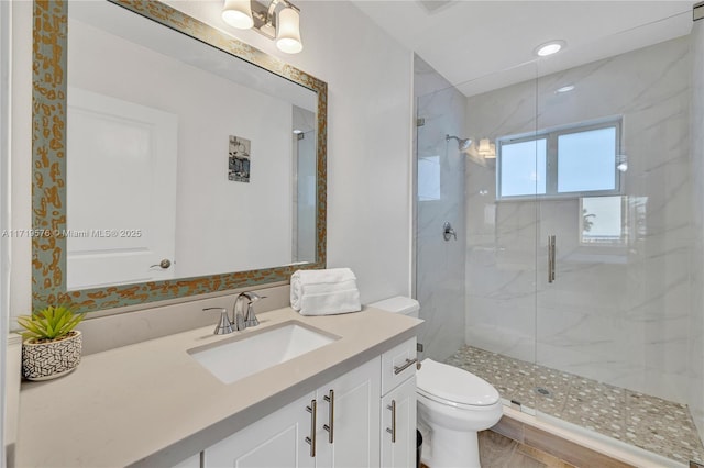 bathroom featuring vanity, toilet, and a shower with shower door