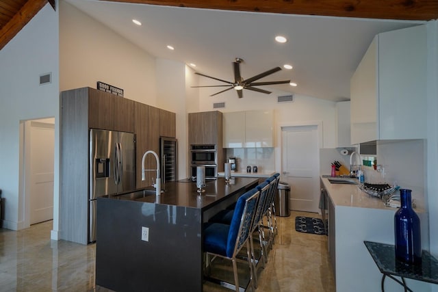 kitchen featuring white cabinetry, an island with sink, sink, a kitchen bar, and stainless steel appliances