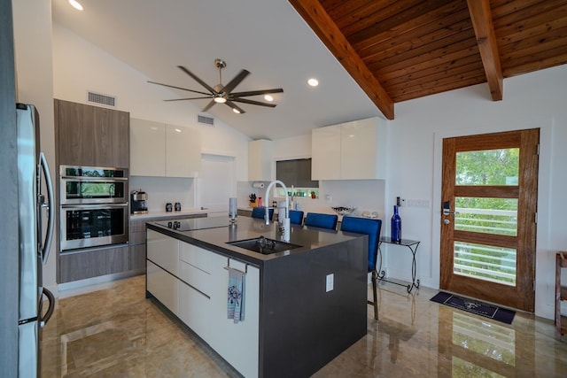 kitchen with sink, stainless steel appliances, an island with sink, and white cabinets