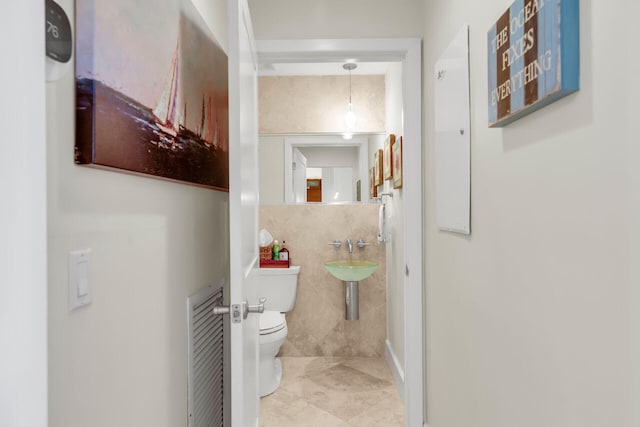 bathroom featuring tile walls, tile patterned floors, and toilet