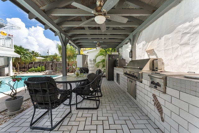 view of patio with area for grilling, a fenced in pool, and exterior kitchen