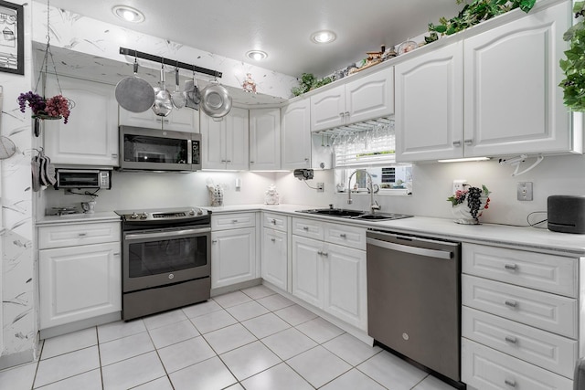 kitchen featuring white cabinetry, sink, light tile patterned floors, and appliances with stainless steel finishes