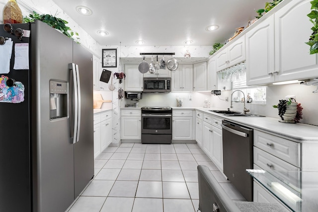 kitchen featuring sink, light tile patterned flooring, white cabinets, and appliances with stainless steel finishes