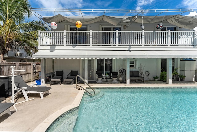 rear view of property with a fenced in pool, a patio area, and a balcony