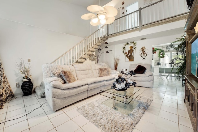 tiled living room with ceiling fan and a high ceiling