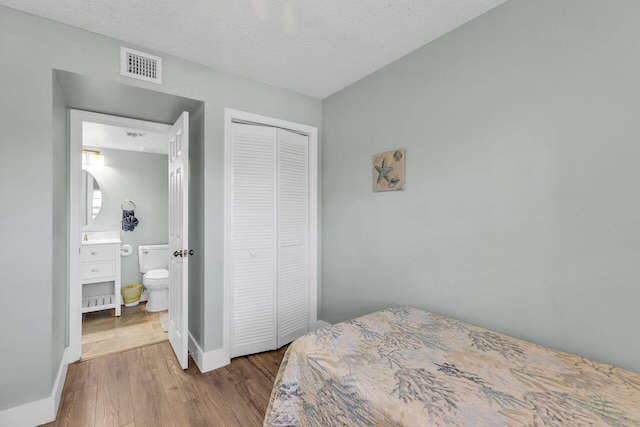 bedroom with light hardwood / wood-style floors, a closet, and a textured ceiling