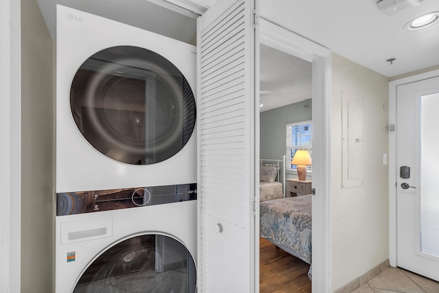 laundry room with stacked washer / dryer and light tile patterned floors