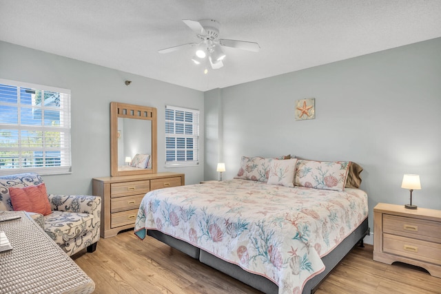 bedroom with ceiling fan, light hardwood / wood-style flooring, and a textured ceiling