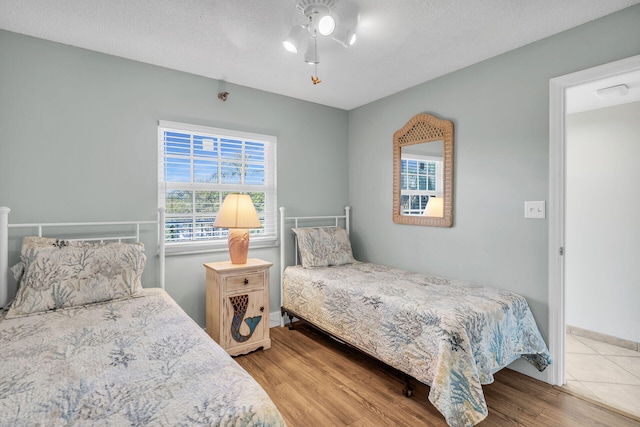 bedroom featuring hardwood / wood-style flooring, ceiling fan, and a textured ceiling