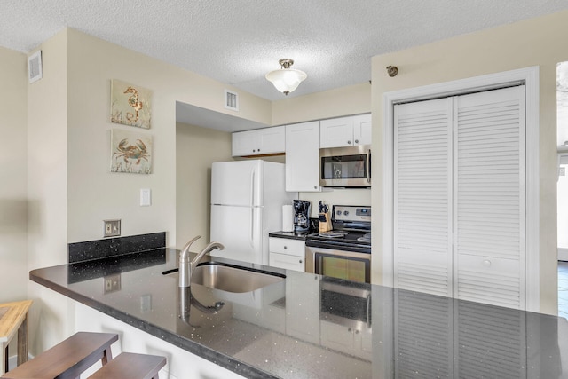 kitchen with appliances with stainless steel finishes, a breakfast bar, sink, white cabinets, and kitchen peninsula