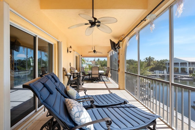 sunroom featuring tile patterned flooring, ceiling fan, and outdoor dining space
