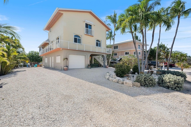 exterior space with a garage, stucco siding, and gravel driveway