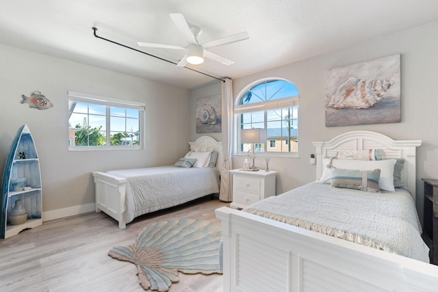 bedroom with a ceiling fan, baseboards, and light wood finished floors
