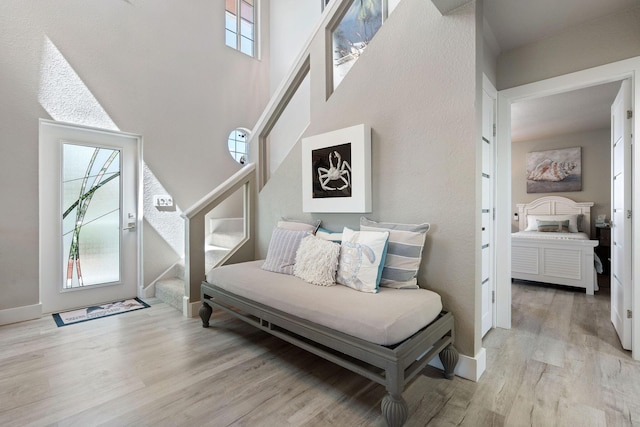 living area featuring baseboards, light wood finished floors, and stairs