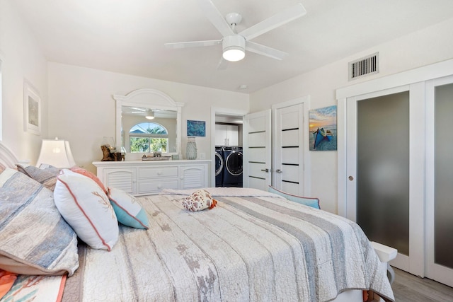 bedroom with a ceiling fan, independent washer and dryer, visible vents, two closets, and light wood-style flooring