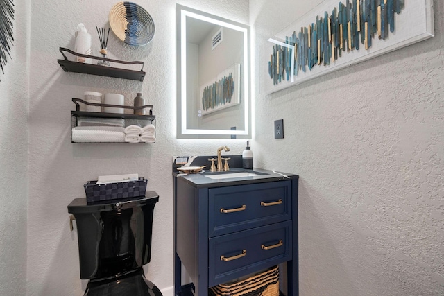 bathroom with a textured wall, visible vents, and vanity