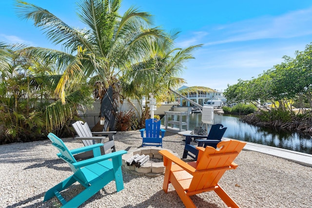 view of patio with boat lift, a water view, a dock, and an outdoor fire pit
