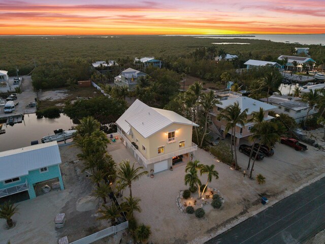 aerial view at dusk featuring a water view and a forest view