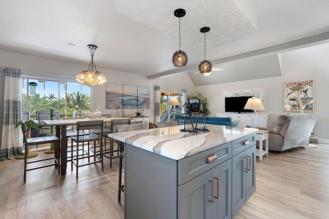 kitchen with light stone counters, gray cabinets, light wood-type flooring, and open floor plan
