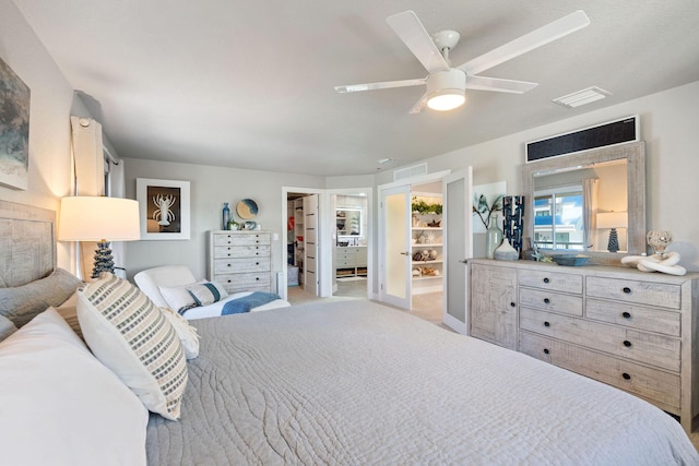 bedroom featuring a walk in closet, a ceiling fan, visible vents, a closet, and light carpet