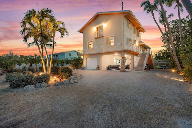 view of front of house featuring a garage, a balcony, stucco siding, driveway, and stairway