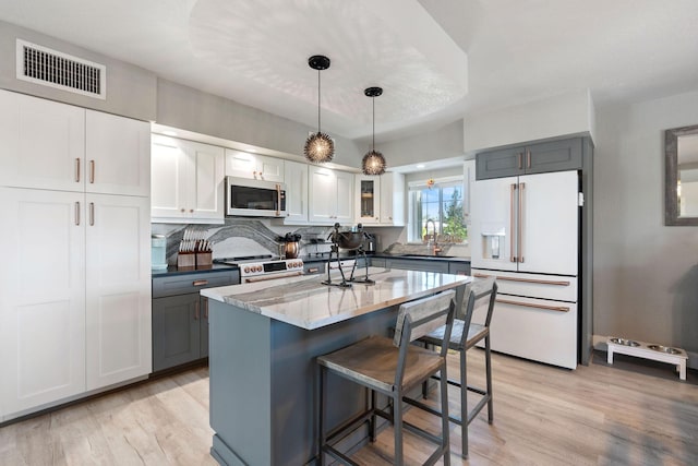 kitchen with visible vents, light wood finished floors, a breakfast bar area, and white appliances