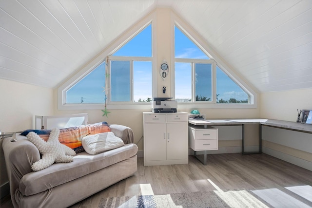 interior space with baseboards, light wood finished floors, and lofted ceiling