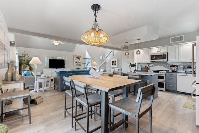 dining room featuring visible vents, ceiling fan with notable chandelier, and light wood-style floors