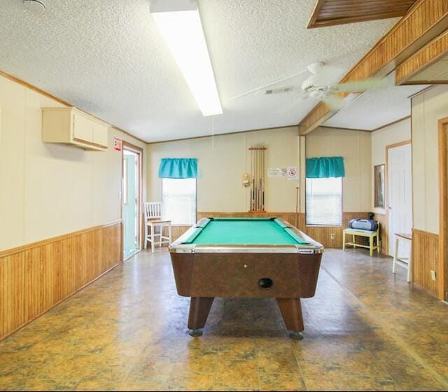 recreation room with a healthy amount of sunlight, a wainscoted wall, ceiling fan, and wooden walls