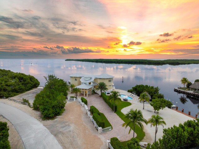 aerial view at dusk featuring a water view