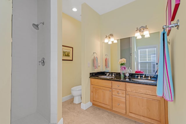 bathroom featuring tiled shower, vanity, toilet, and tile patterned flooring