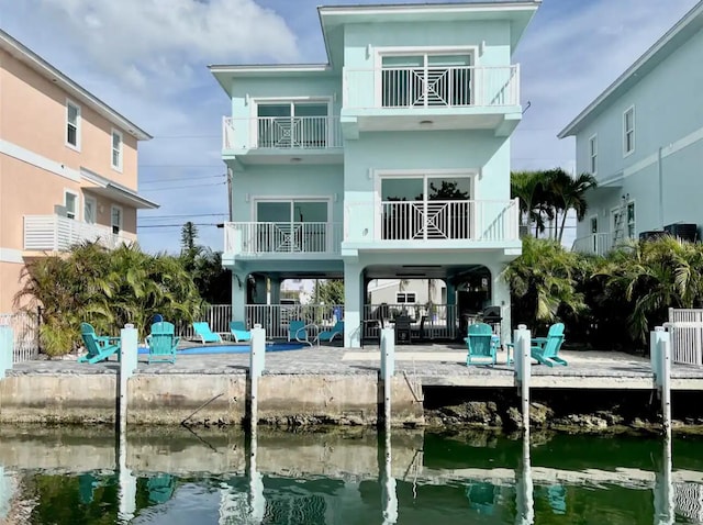 rear view of property featuring stucco siding, a water view, fence, and a patio area