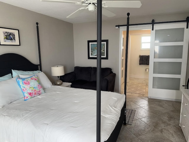 bedroom with a barn door, connected bathroom, and ceiling fan