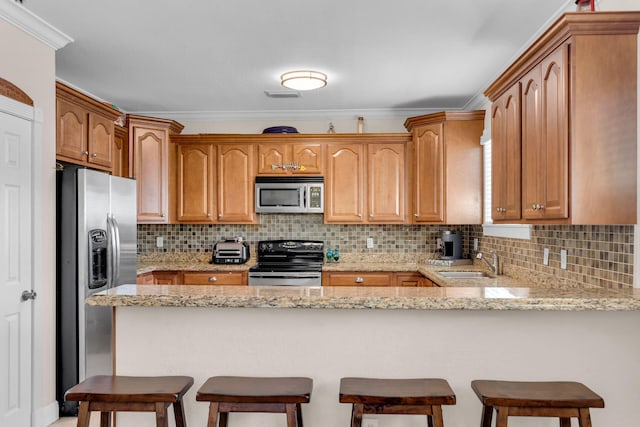 kitchen with light stone counters, a breakfast bar area, a peninsula, appliances with stainless steel finishes, and tasteful backsplash